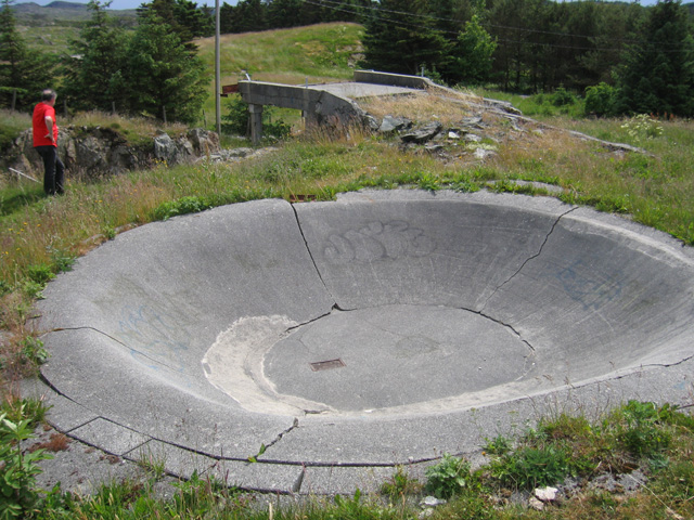 En 'betong-kumme' med rist i bunn og en 'rampe' i bakgrunnen.