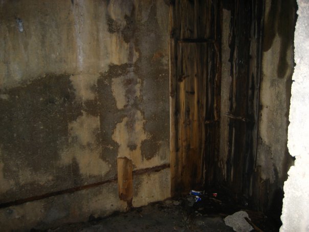 Inne i det bakre rommet i kommandobunkeren. Ser ut til at veggene var kledd i trevær når bunkeren var i bruk. Rester etter kabler i taket...