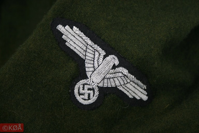 Ørn på ermet. Den er veldig fint brodert, øverste del av vingene har en metallisk tråd med mer sølvglans, mens resten av ørnen har en mattere glans.