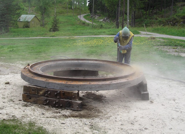 Sandblåsing av Cockerill kanons nedre dreiring med tannkrans på Høytorp fort, sommeren 2010.