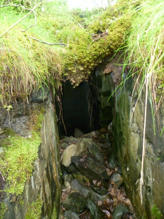 Nede i løpegraven. En delvis gjenfylt og sammenrast dekningsbunker av mindre type kan vi skimte her.