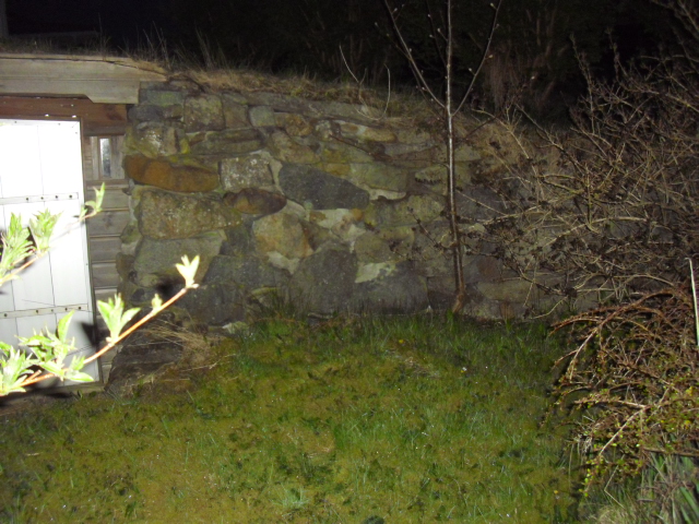 Fasademuren var formet som en halvsirkel med døra i midtten . Man kan se at fasaden i tre er blitt fornyet med årene og steinene er murt opp med sement.