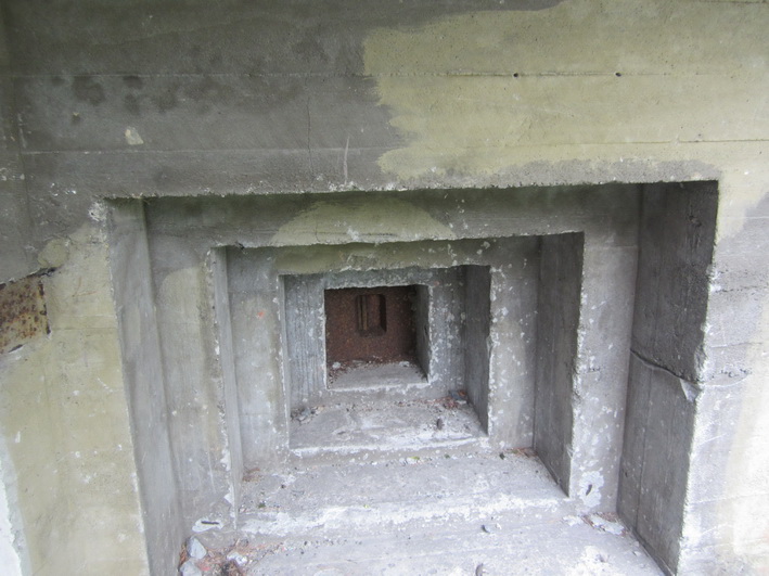 R-105 bunker på Kronå. Bunkeren ligger delvis på privat eiendom, men ser ut til å være både åpen og tilgjengelig. Rester av kamuflasjemalingen i inngangspartiet er fremdeles synlig. Her ser vi skyteskåret v. inngangspartiet.