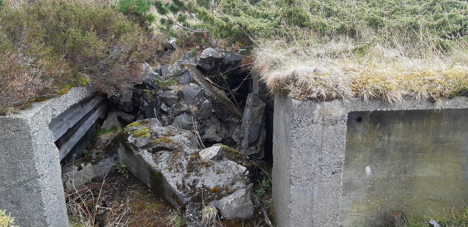 Bildet er tatt inni stillingen for avstandsmåleren, mot &quot;gangen&quot; mellom stillingene, som idag er gjenfylt av debris fra 2cm-stillingen. Vi kan skimte litt av ene ammo&quot;nisjen&quot; til 2cm-stillingen blant stein og betong.